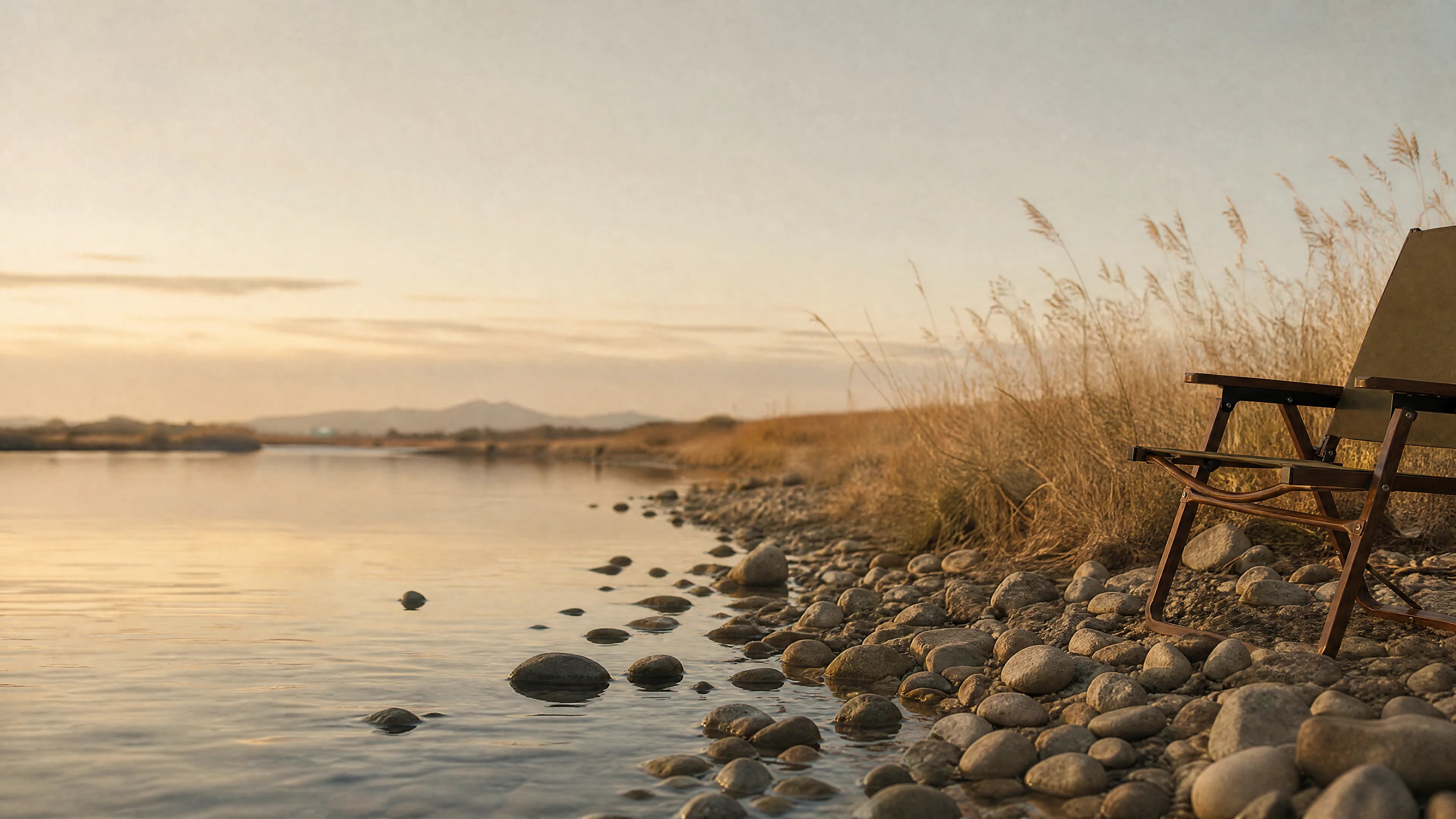 SummitSage chair on a serene pebbled lakeshore at sunset